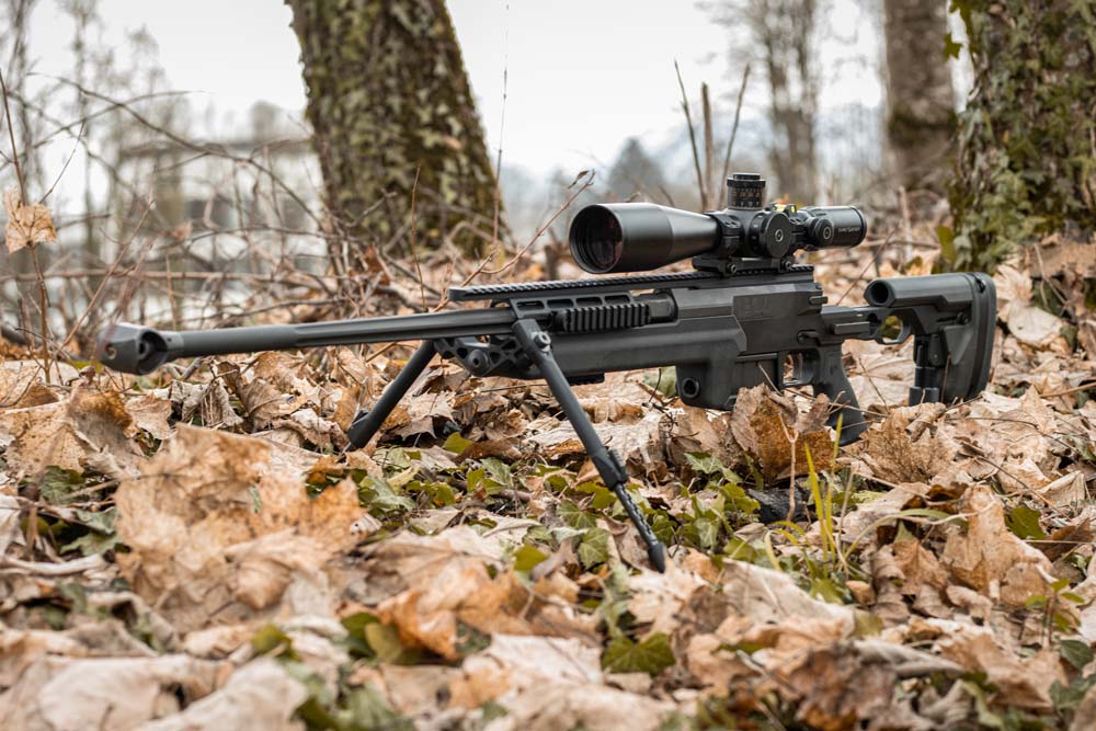 Un fusil de sniper PGM Mini Hécate II équipé d'un bipied PGM ELR dans la forêt.