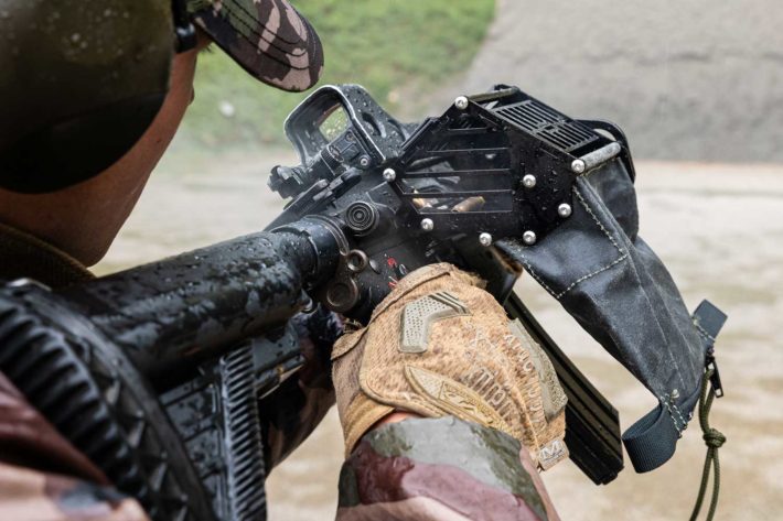Un tireur militaire tir avec un HK416 F de l'armée française équipé du récupérateur d'étuis Kastinger. L'arme est inclinée à 30°, les aérations du récupérateur d'étuis sont à l'horizontal, ce qui signifie qu'il s'agit de la limite d'inclinaison vers la gauche permise par le récupérateur d'étuis.